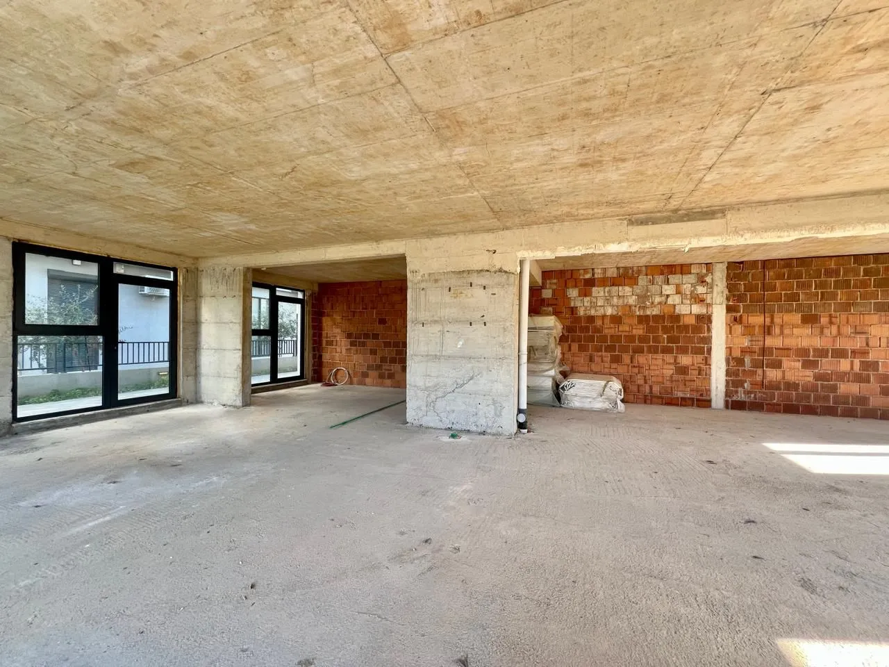 Unfinished bare-shell space with concrete columns and windows.