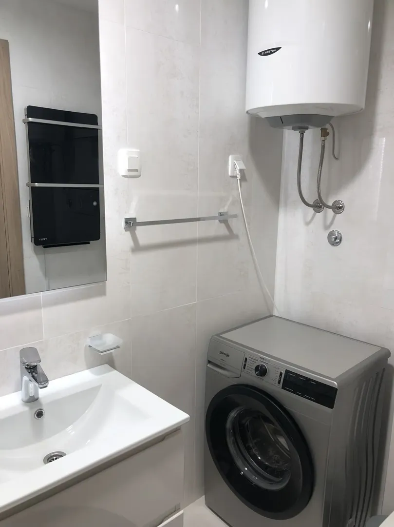 Bright bathroom with a washing machine and sink.