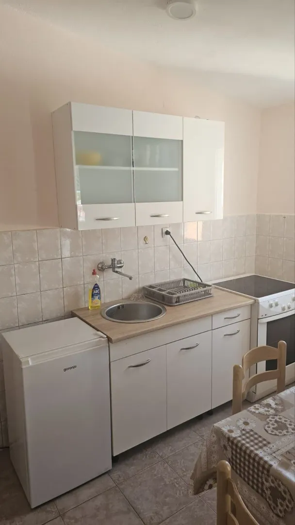 Manja kuhinja sa bijelim elementima, sudoperom i šporetom.