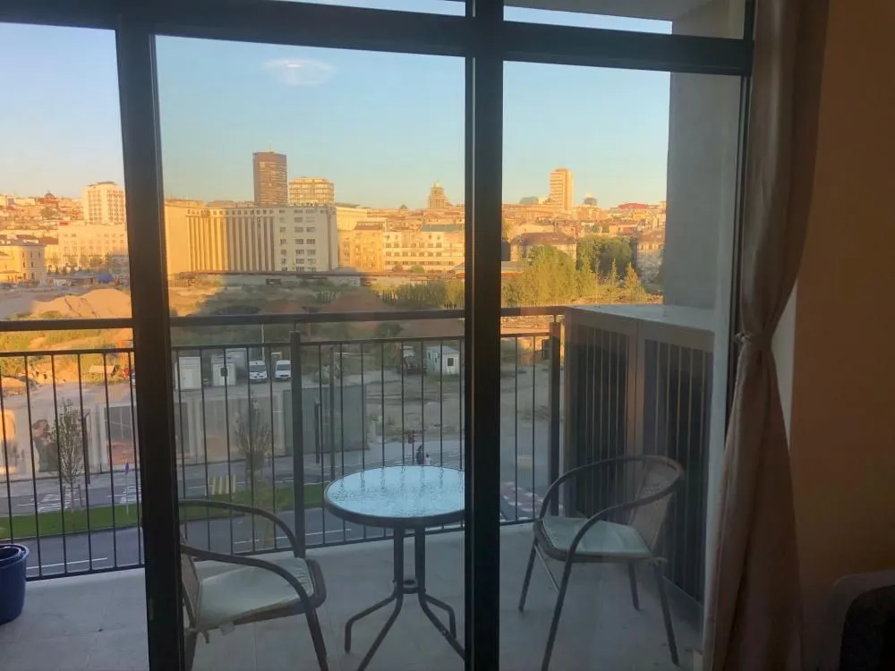 Furnished balcony with a table, chairs, and city view.