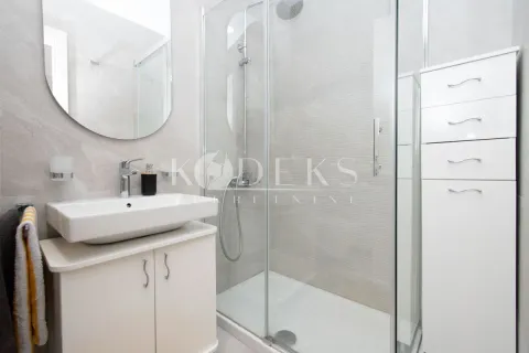 A modern bathroom equipped with a shower cabin, washbasin, and white bathroom furniture. - image 6