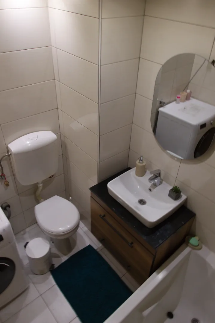 A neatly equipped bathroom with a washbasin, toilet bowl, and mirror.