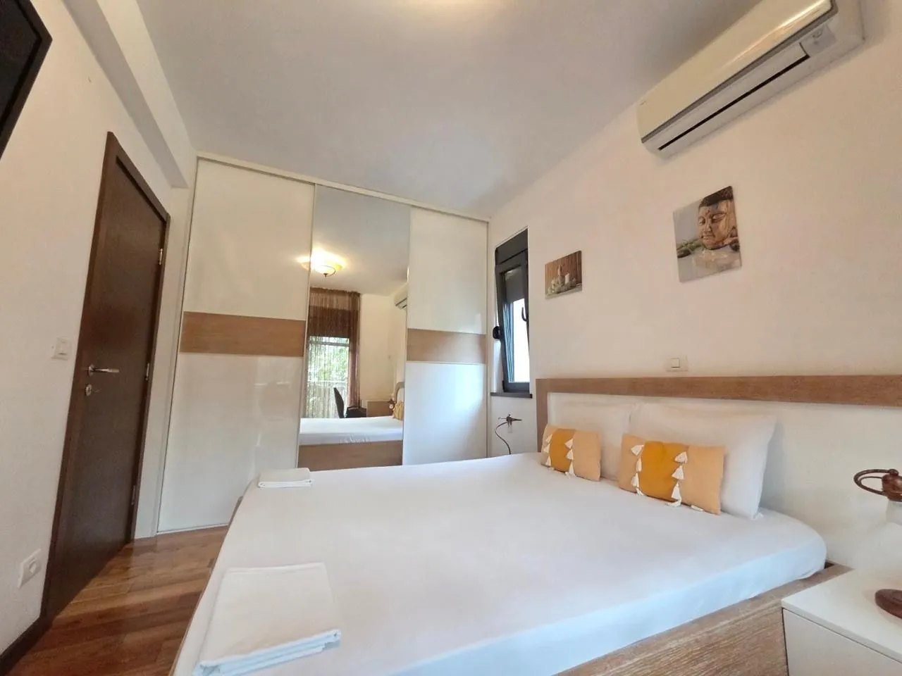 Tidy bedroom with a double bed, wardrobe, and air conditioning.