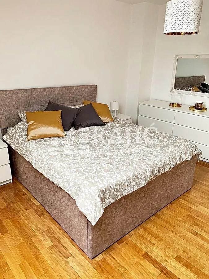 Furnished bedroom with a double bed, dresser, and mirror.