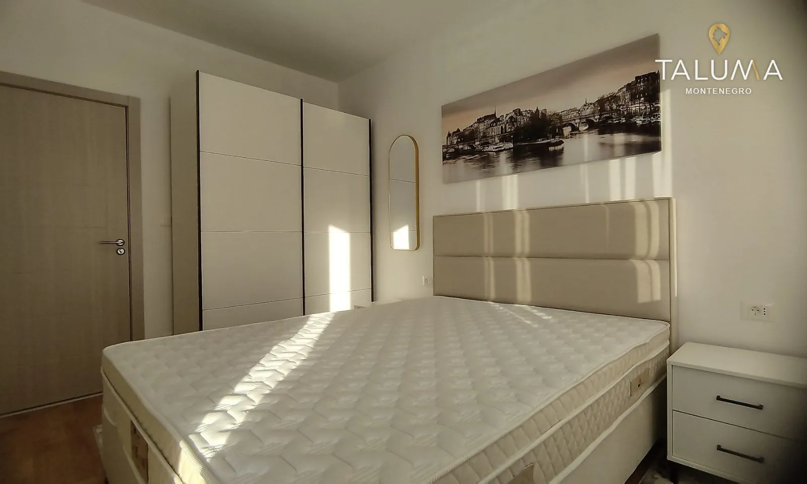 Bright bedroom with a double bed, large wardrobe and bedside table.