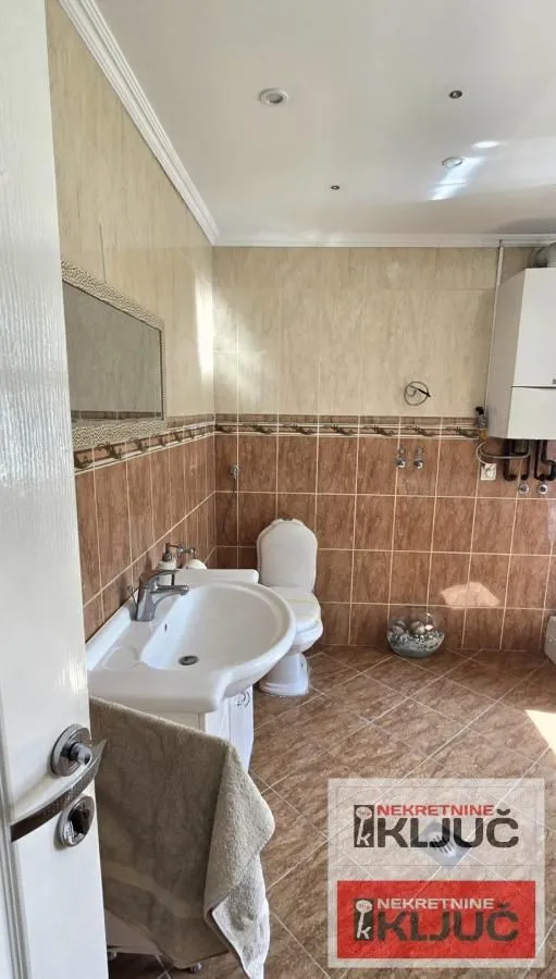 Bathroom tiled with ceramic tiles featuring a sink and toilet.