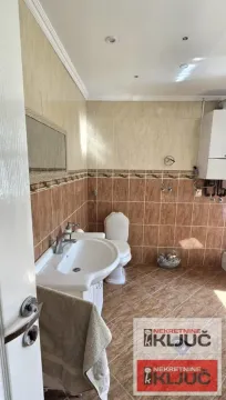 Bathroom tiled with ceramic tiles featuring a sink and toilet. - image 32