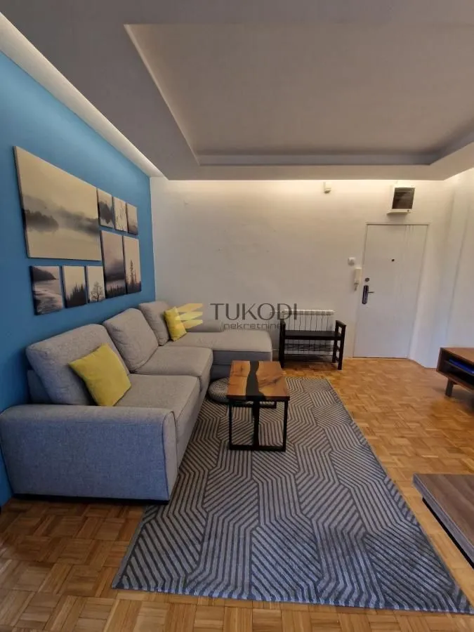 Living room with a sectional sofa, coffee table, and a blue accent wall with pictures.
