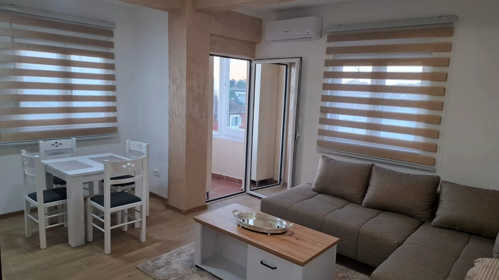 Svijetla dnevna soba sa trpezarijskim stolom i izlazom na balkon.