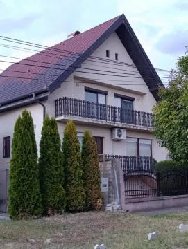 Pogled na spoljašnjost dvospratne kuće sa dvorištem i tujama. - image 2