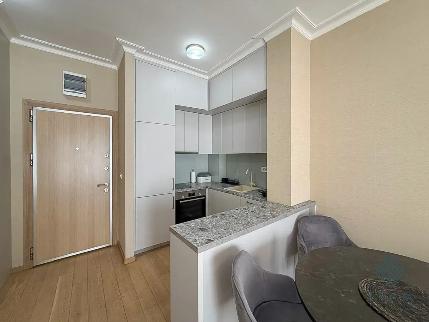 Compact kitchen with white cabinetry and an adjacent dining table.