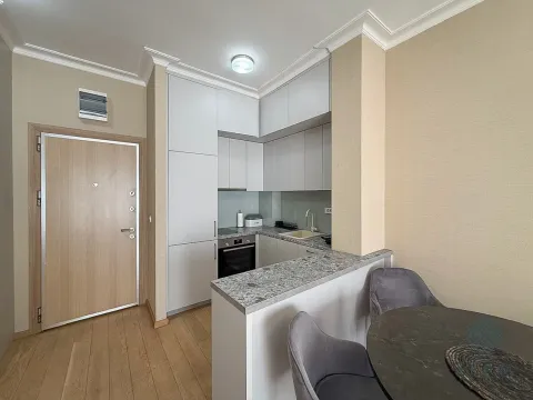 Compact kitchen with white cabinetry and an adjacent dining table. - image 4