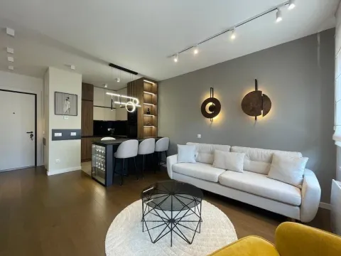 Modern living room with a sofa, coffee table, and an open-plan kitchen. - image 5