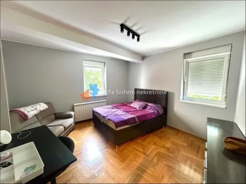 Furnished bedroom with a double bed, a sofa, and parquet flooring. - image 9