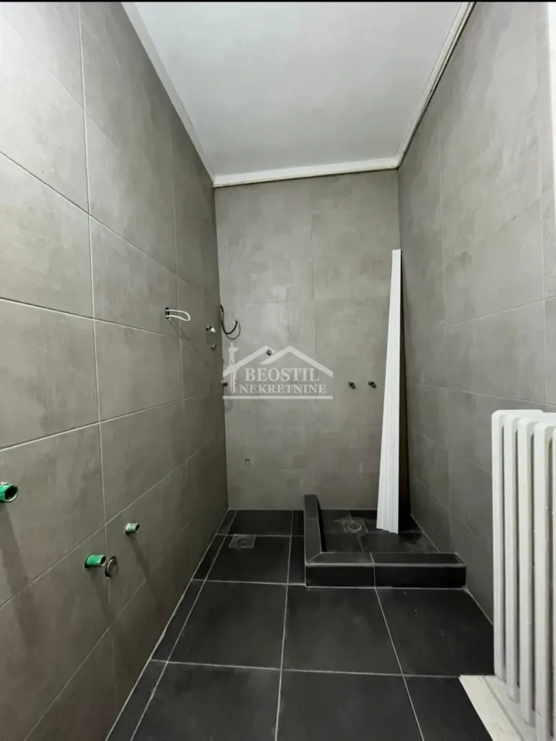 Kupatilo u fazi opremanja sa sivim pločicama i pripremljenim instalacijama.