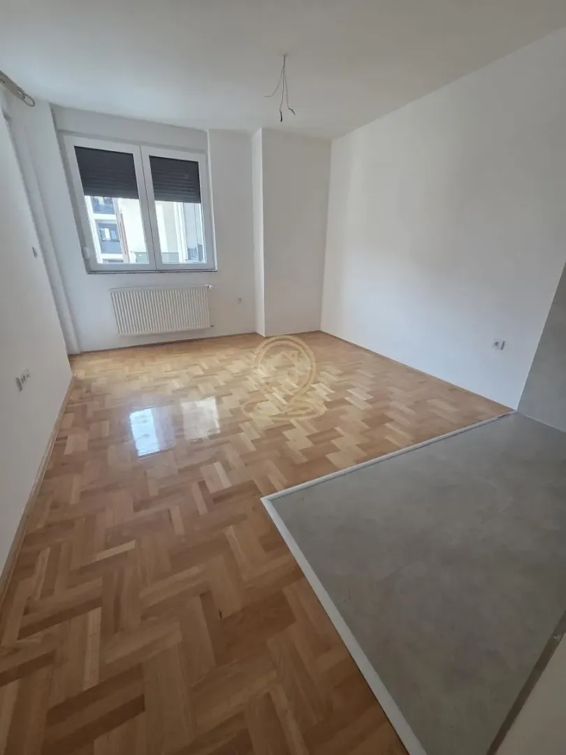 Prazna soba sa parketom i prozorom.