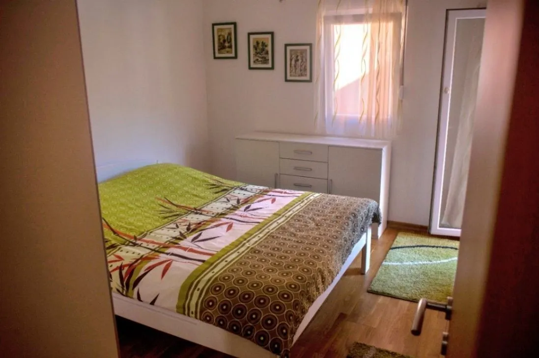 Jednostavno namještena spavaća soba sa bračnim krevetom i komodom.