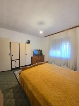 Namještena spavaća soba sa bračnim krevetom, ormarom i prozorom sa bijelim zavjesama. - image 10