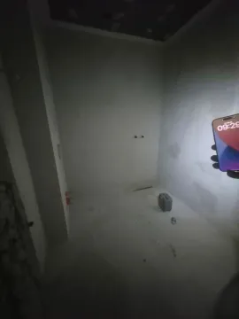 Neopremljena prostorija u fazi grubih radova sa telefonom u ruci. - image 4