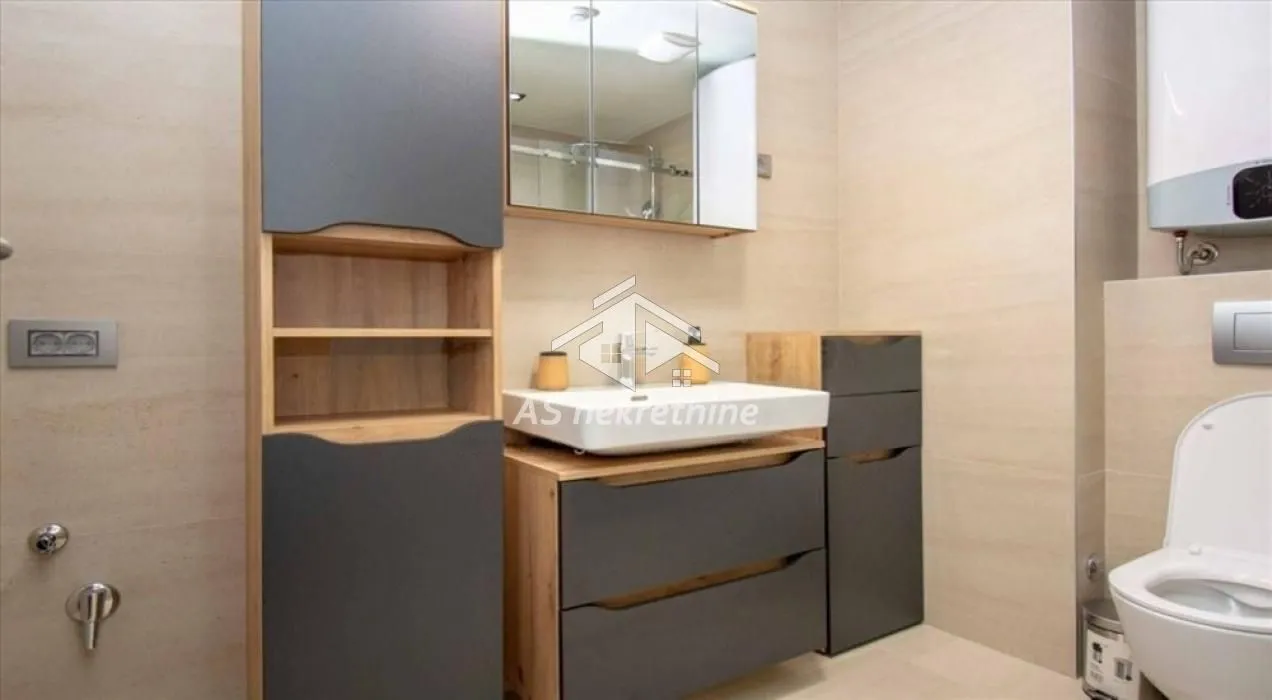 Modern bathroom equipped with a sink, cabinets, mirror, and toilet.