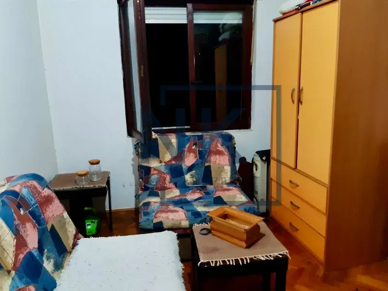 Manja spavaća soba sa krevetom, ormarom i prozorom.