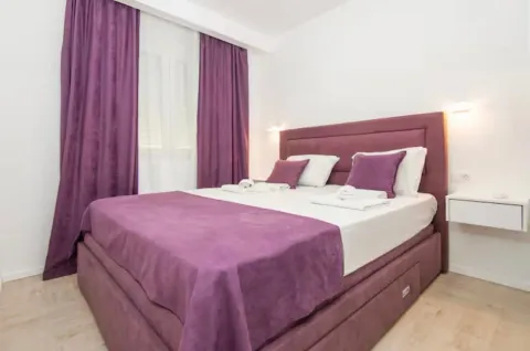 Furnished bedroom with a double bed and purple details. - image 10