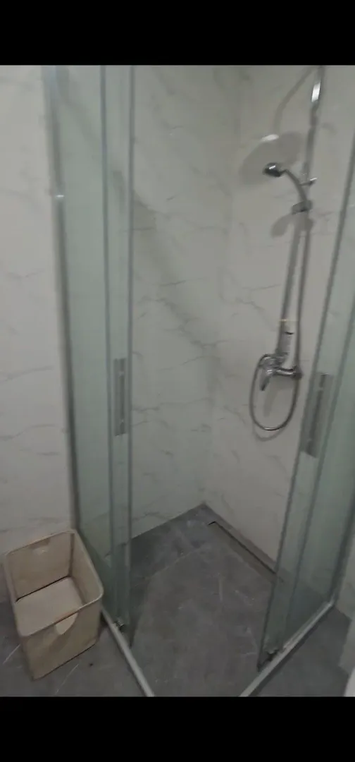 Modern walk-in shower with marble-look tiles in a bathroom.