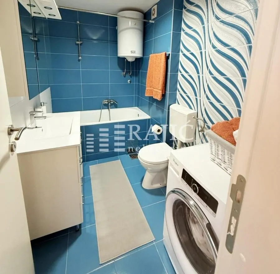 Small bathroom with a bathtub, washbasin, and washing machine.