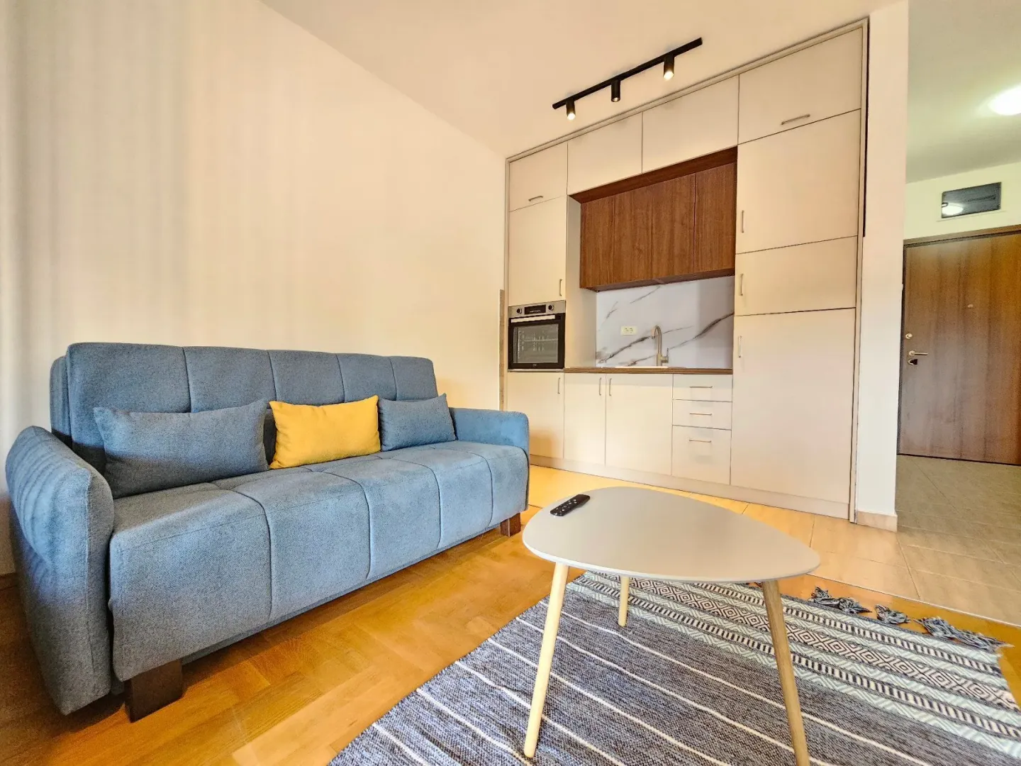 Living room with a blue sofa, coffee table, and an integrated kitchen.