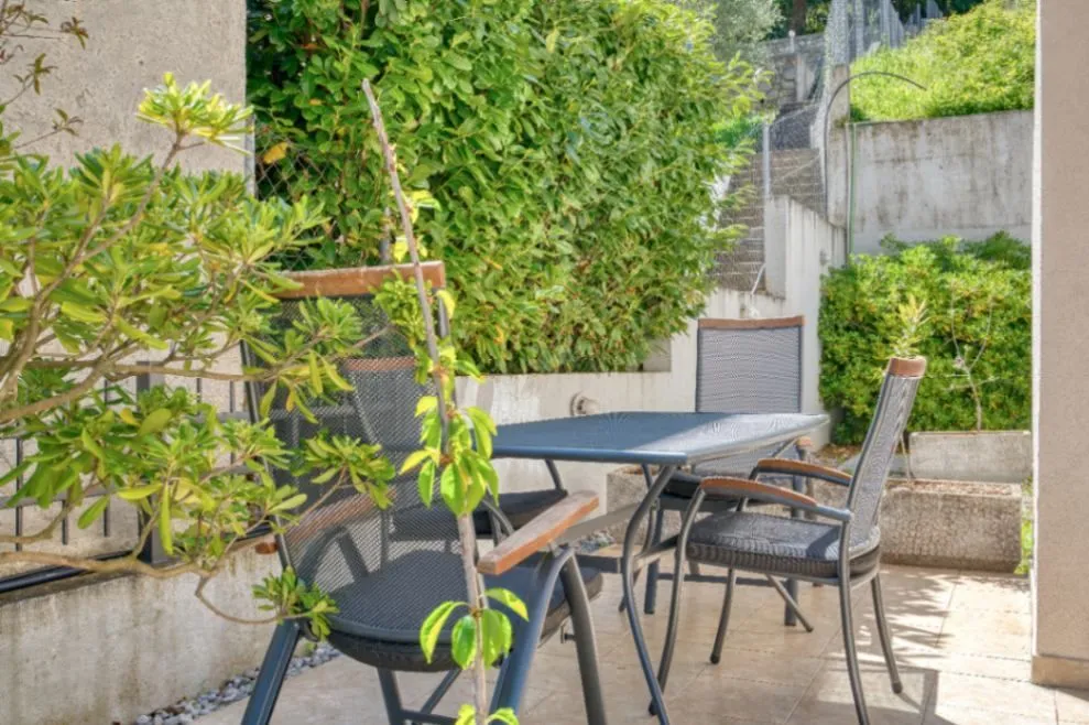 Terrace with a table and chairs surrounded by greenery.