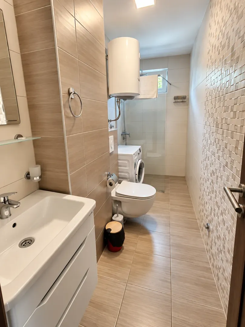 Moderne opremljeno kupatilo sa tuš kabinom, umivaonikom i veš mašinom.