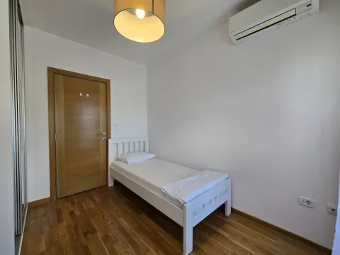 Small bedroom with a white single bed, wooden flooring, and an air conditioner. - image 8