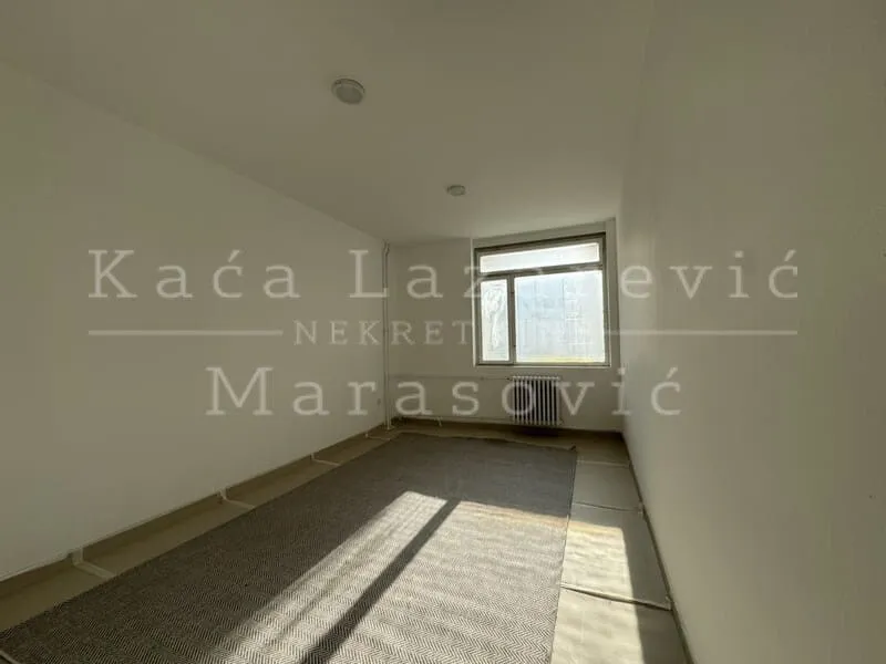 Empty unformatted room with a window and a rug on the floor.