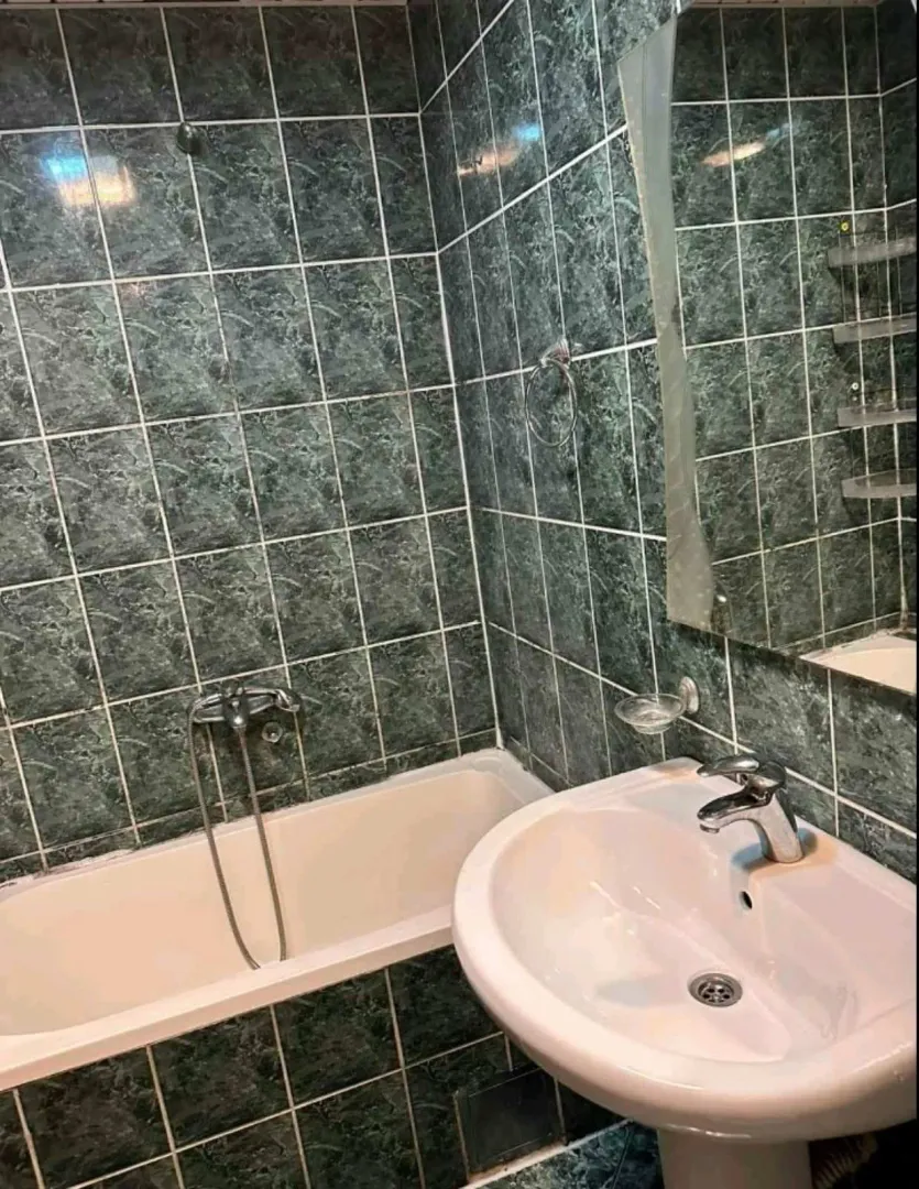 Bathroom with green tiles, a bathtub, and a sink.