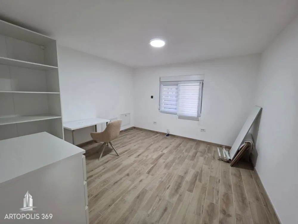 Empty room with white walls, laminate flooring, and a desk.