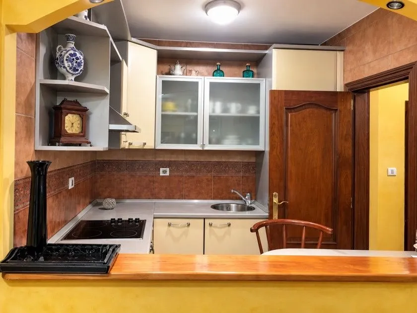 Manja opremljena kuhinja sa drvenim elementima i šankom.