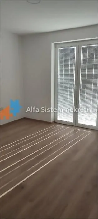 Empty room with laminate flooring and balcony doors.