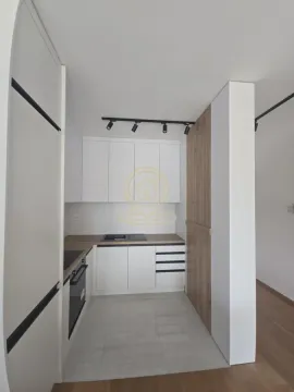 Moderna kuhinja sa belim elementima i drvenim detaljima. - image 12
