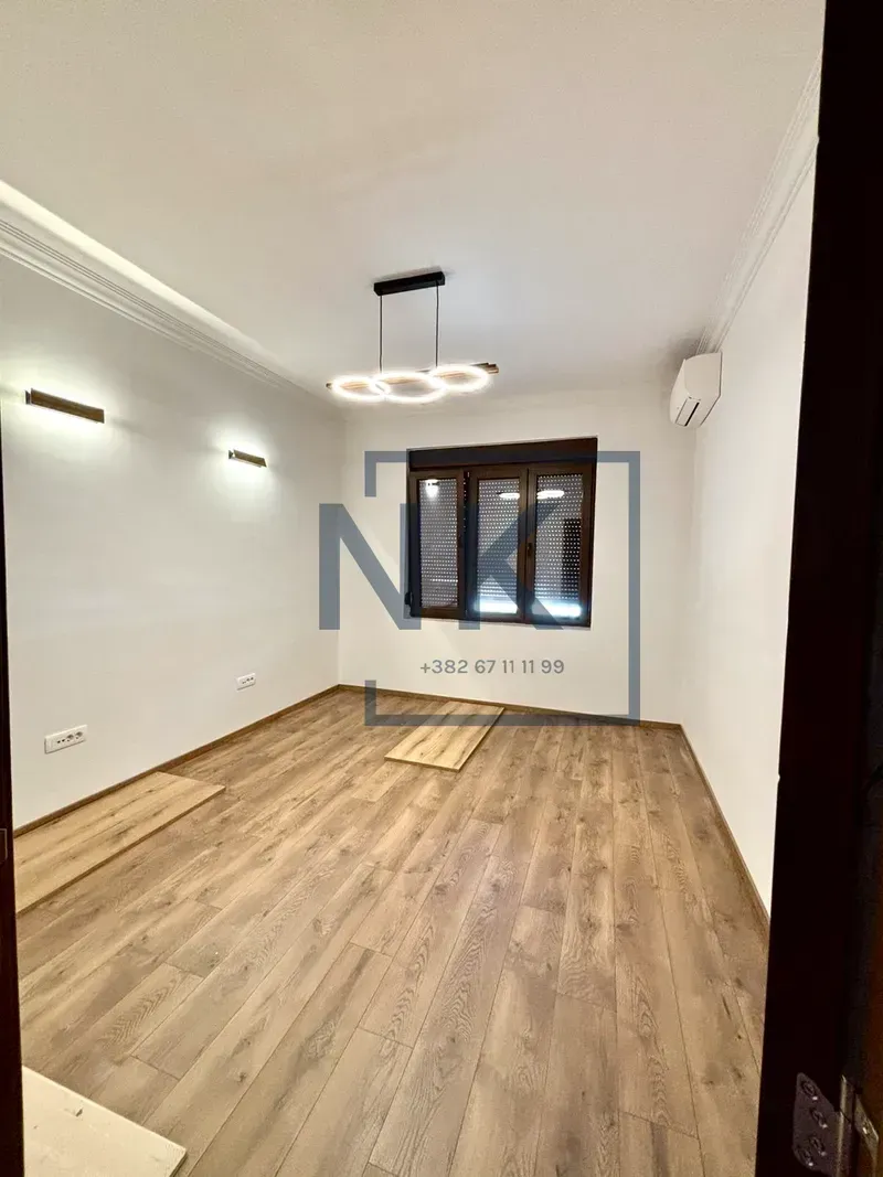Empty room with hardwood floors, a window, and lighting.