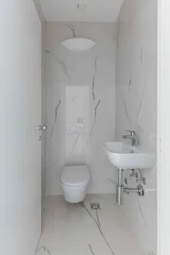 Manje kupatilo sa WC šoljom i umivaonikom obloženo mermernim pločicama. - image 32