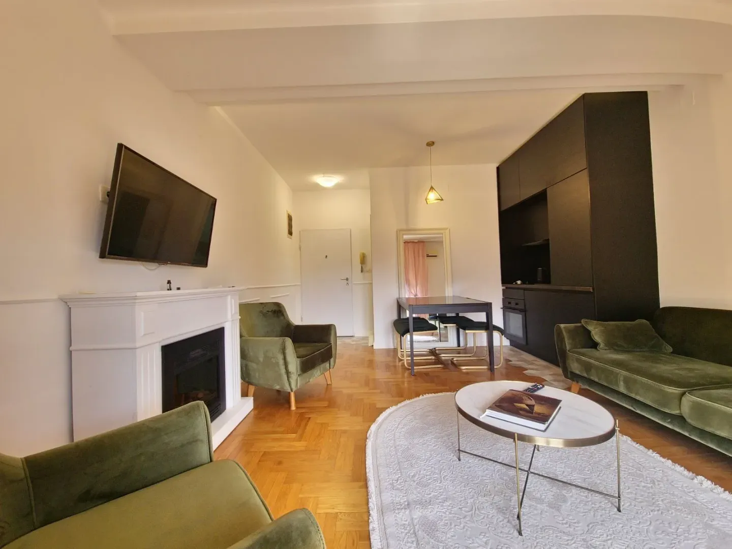 Living room with sofa set, fireplace and kitchen corner in the background.