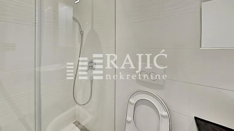 Modern equipped bathroom with a shower cabin and white tiles.