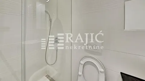 Modern equipped bathroom with a shower cabin and white tiles. - image 15