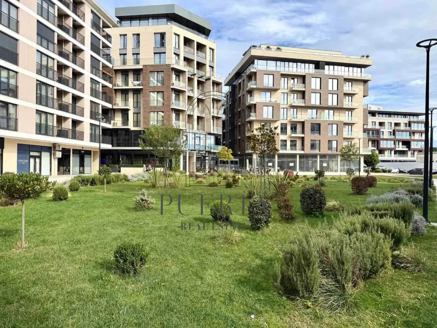 Modern residential buildings with a landscaped courtyard and lawn.