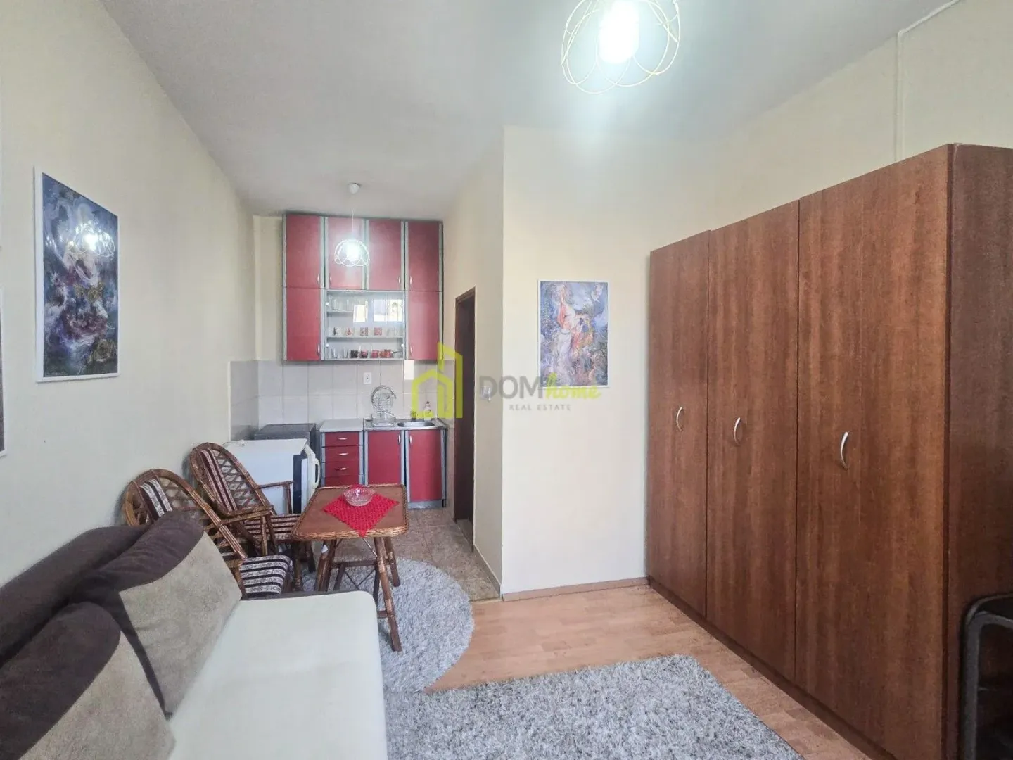 Living room with a sofa, built-in wardrobe, and a corner kitchen area.