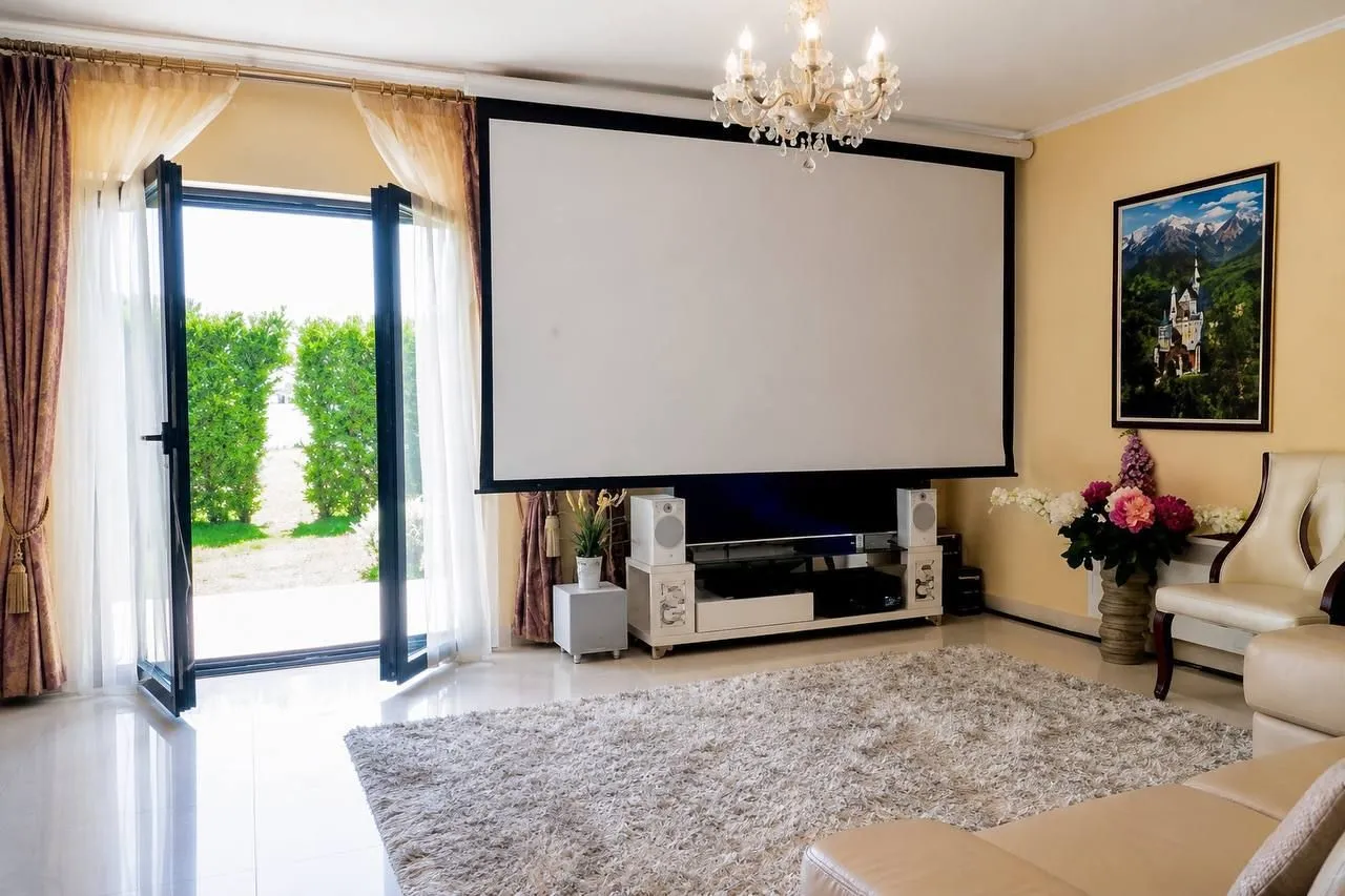 Spacious living room with a large projector screen and access to the yard.