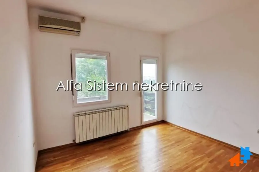 Empty room with hardwood flooring, radiator and air conditioning unit.