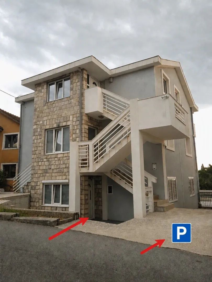 Spoljašnji izgled višespratne kuće sa kamenom fasadom i spoljnim stepeništem.