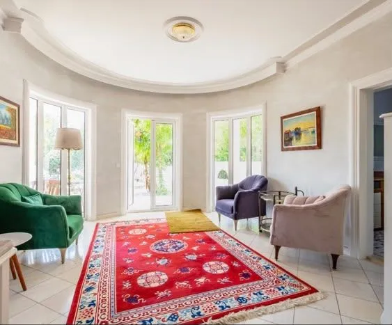 Spacious living room with seating furniture and large windows.