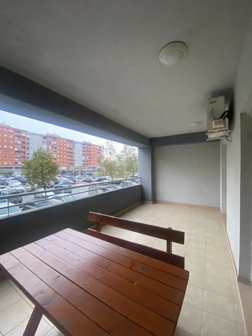A spacious balcony featuring a wooden table and bench.